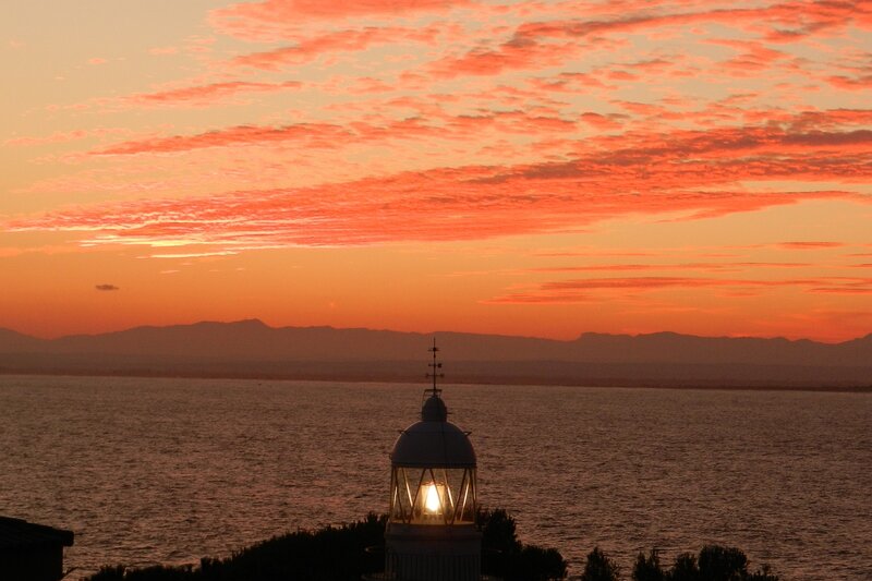 Lighthouse at Sunset — Orange, Serene, Photograph, Sea, Mountains