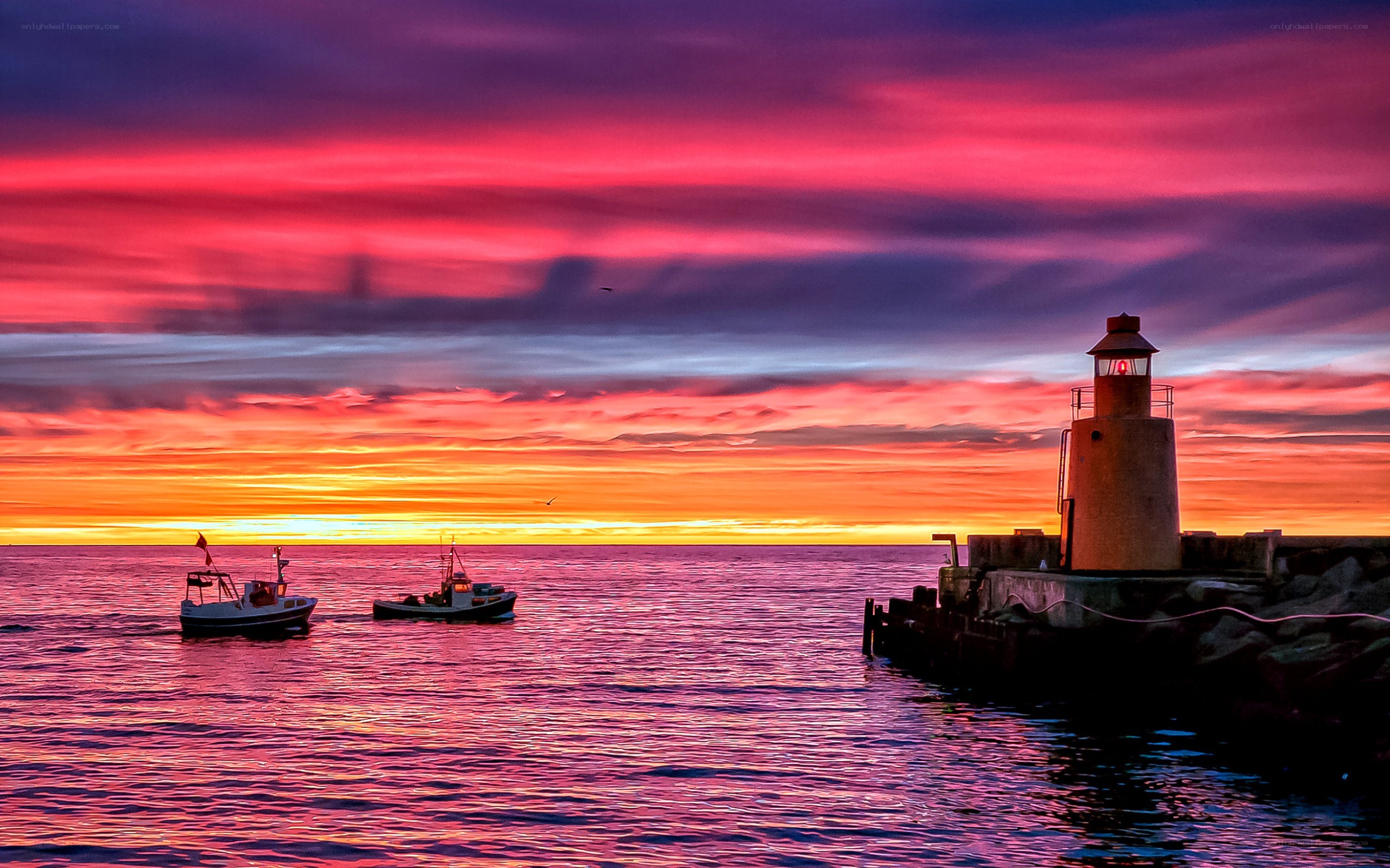 Lighthouse at sunset with boats