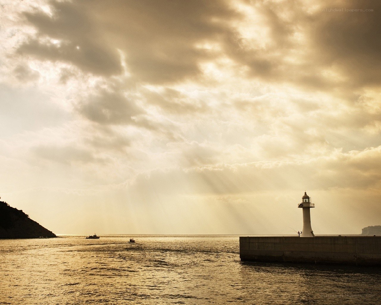 Lighthouse at sunset with boats