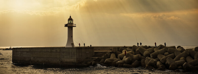 Lighthouse at sunset with fishermen