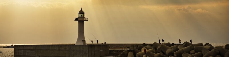 Lighthouse at sunset with fishermen