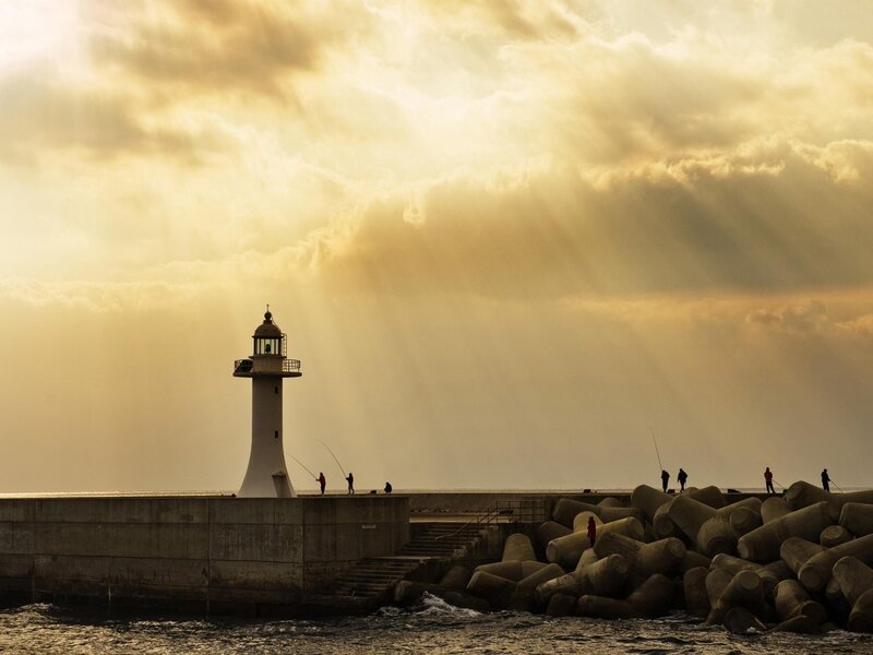 Lighthouse at sunset with fishermen