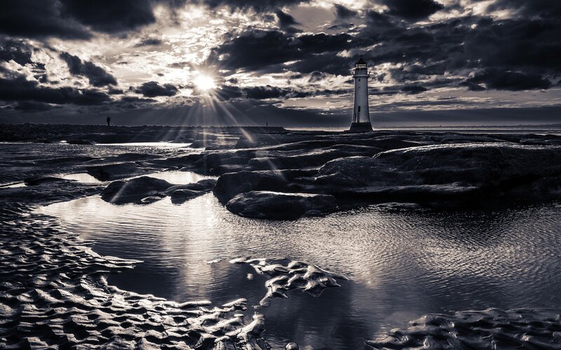 Lighthouse at sunset with sun rays