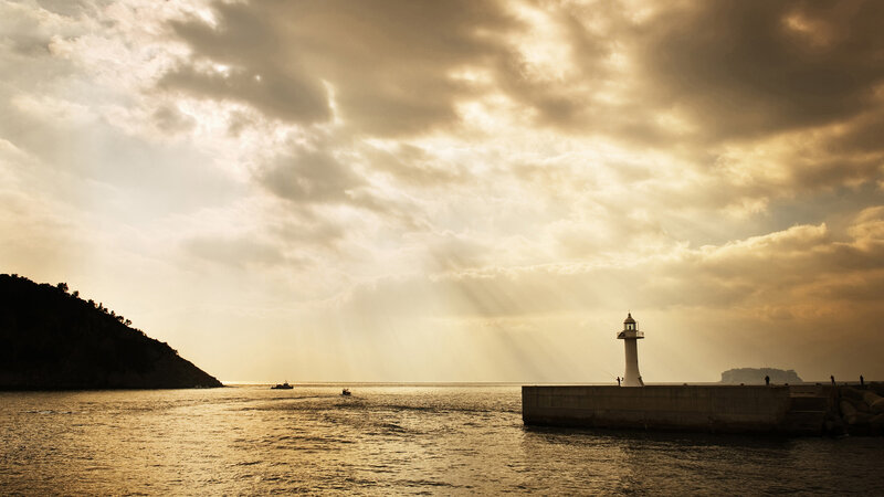 Lighthouse at sunset with sunbeams