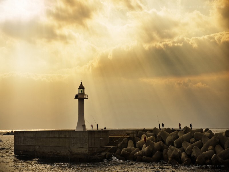 Lighthouse at sunset with sunbeams