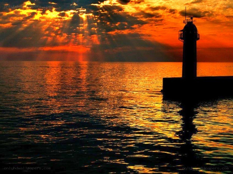 Lighthouse at sunset with sunbeams