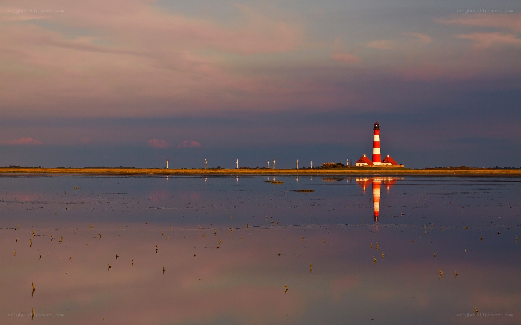 Lighthouse at sunset with wind turbines