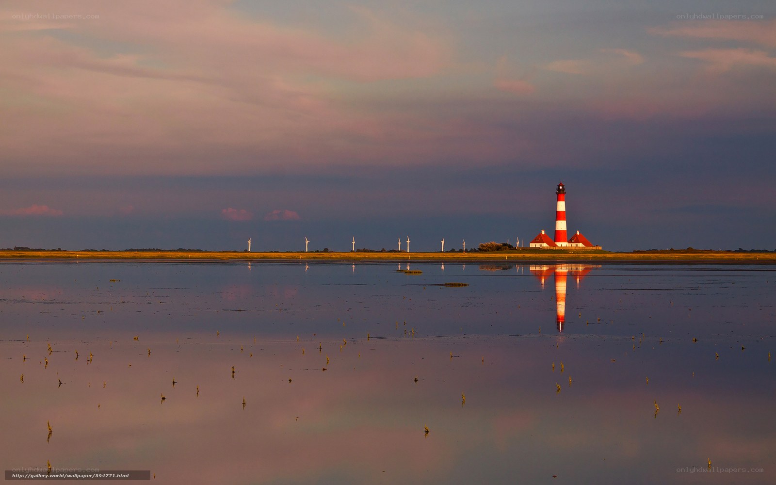 Lighthouse at sunset with wind turbines