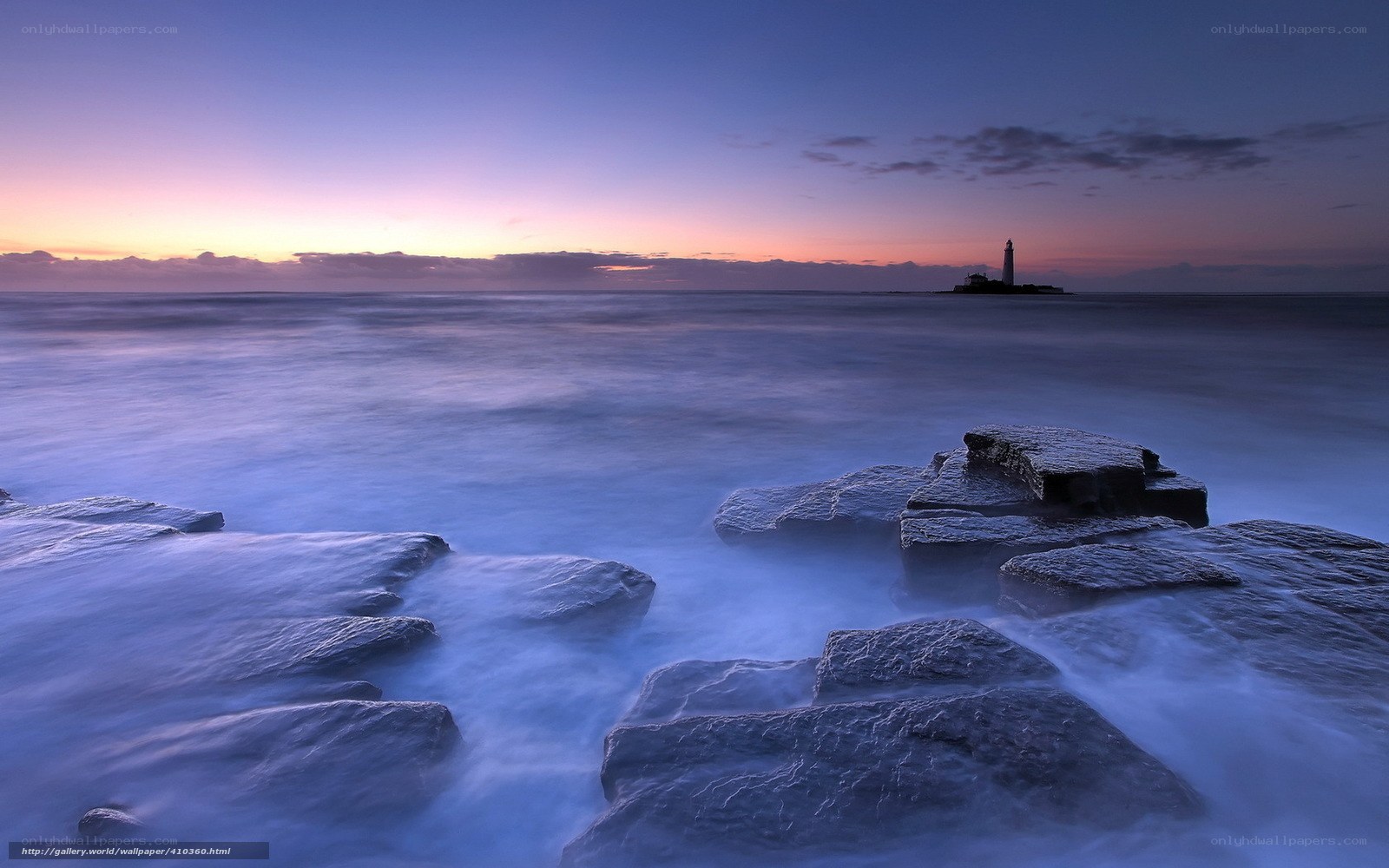 Lighthouse at twilight on rocky shore