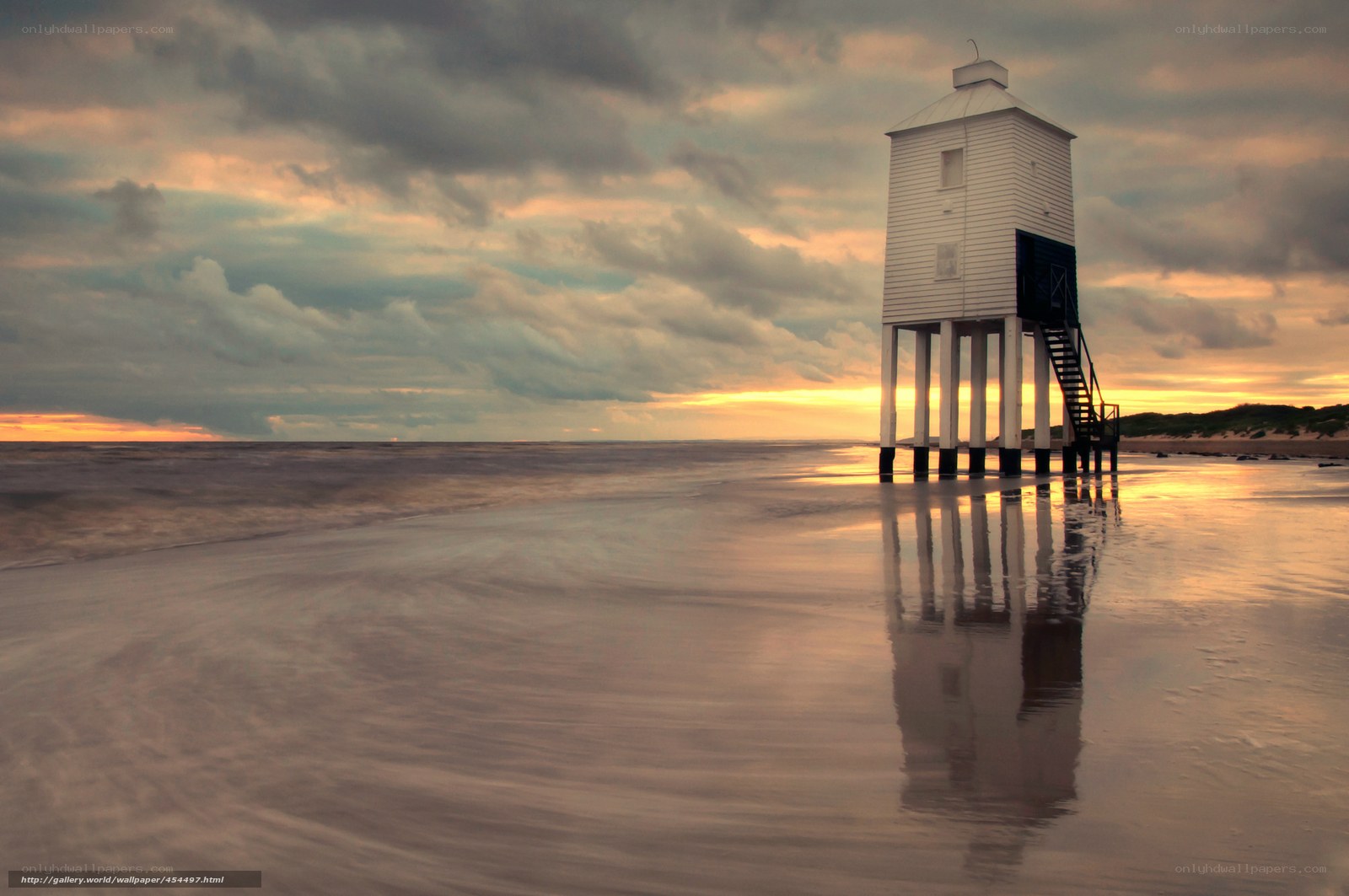 Lighthouse on a beach at sunset