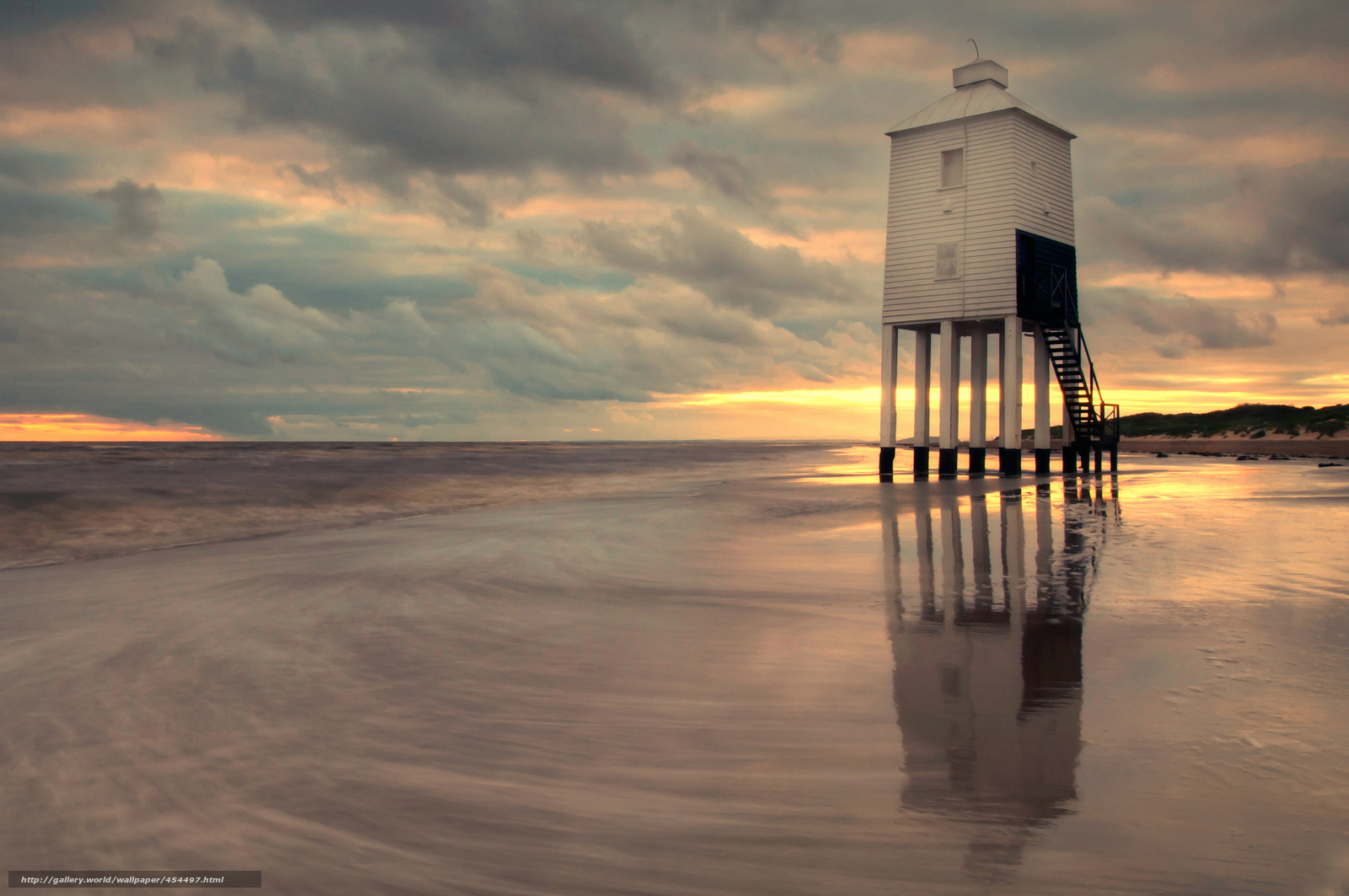 Lighthouse on a beach at sunset