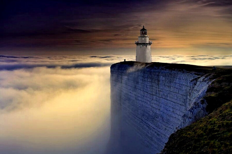 Lighthouse on a cliff above clouds