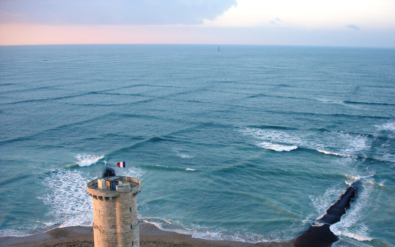 Lighthouse on Cliff — Blue, Serene, Sunset, Photograph, Ocean, Flag