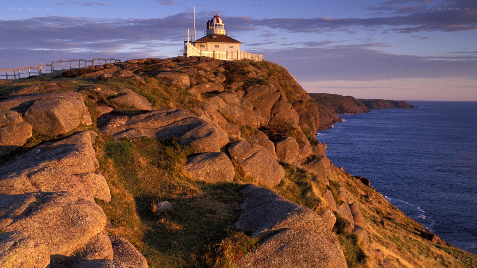 Lighthouse on rocky cliff at sunset
