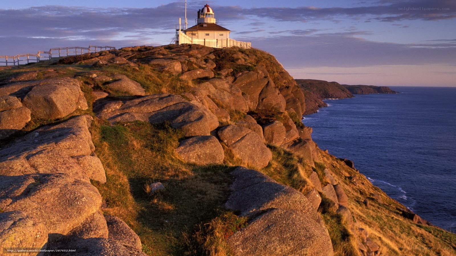 Lighthouse on rocky cliff at sunset
