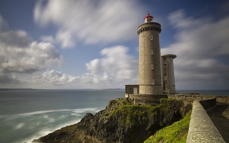 Lighthouse on Rocky Cliff — Blue, Dramatic, Afternoon, Photograph, Ocean, Sky, Clouds