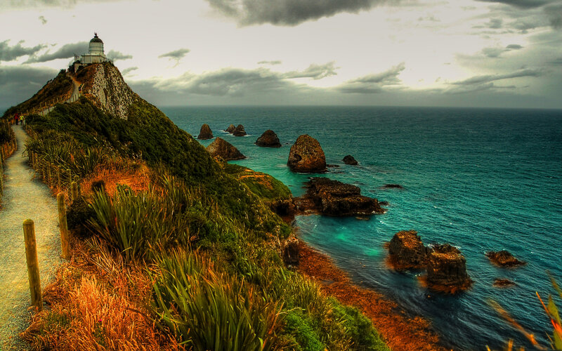 Lighthouse on Rocky Cliff — Blue, Dramatic, Afternoon, Photograph, Ocean