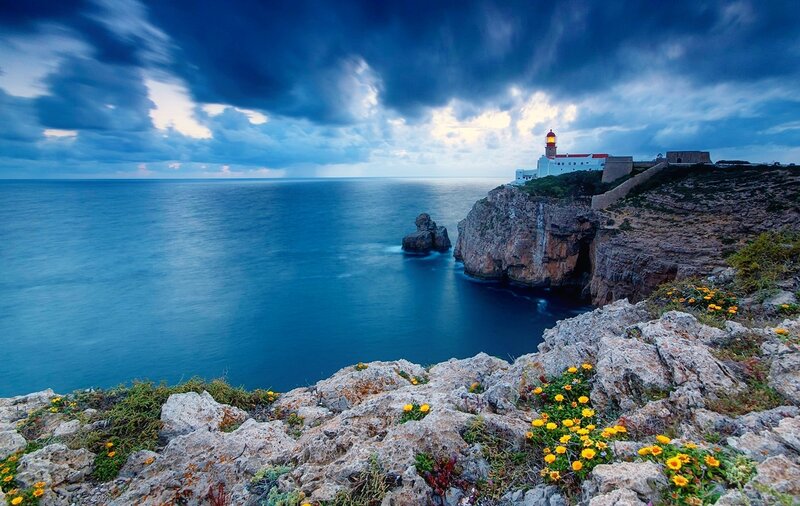 Lighthouse on Rocky Cliff — Blue, Dramatic, Sunset, Photograph, Ocean, Clouds, Flowers