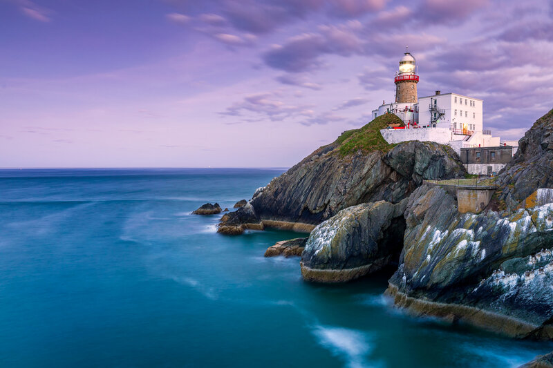 Lighthouse on Rocky Cliff — Blue, Serene, Sunset, Photograph, Ocean, Sky, Rocks