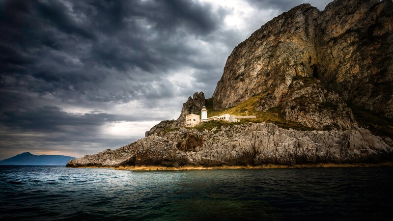 Lighthouse on Rocky Cliff — Gray, Dramatic, Sunset, Photograph