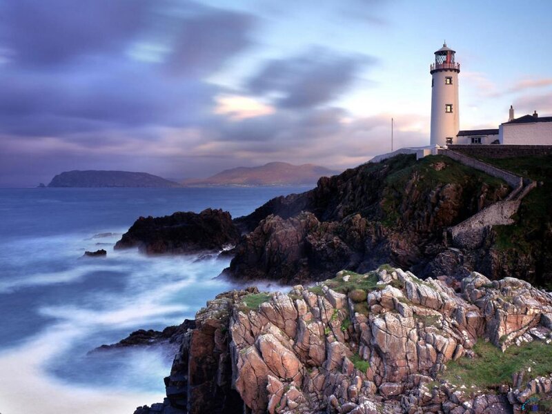 Lighthouse on rocky coast at dusk