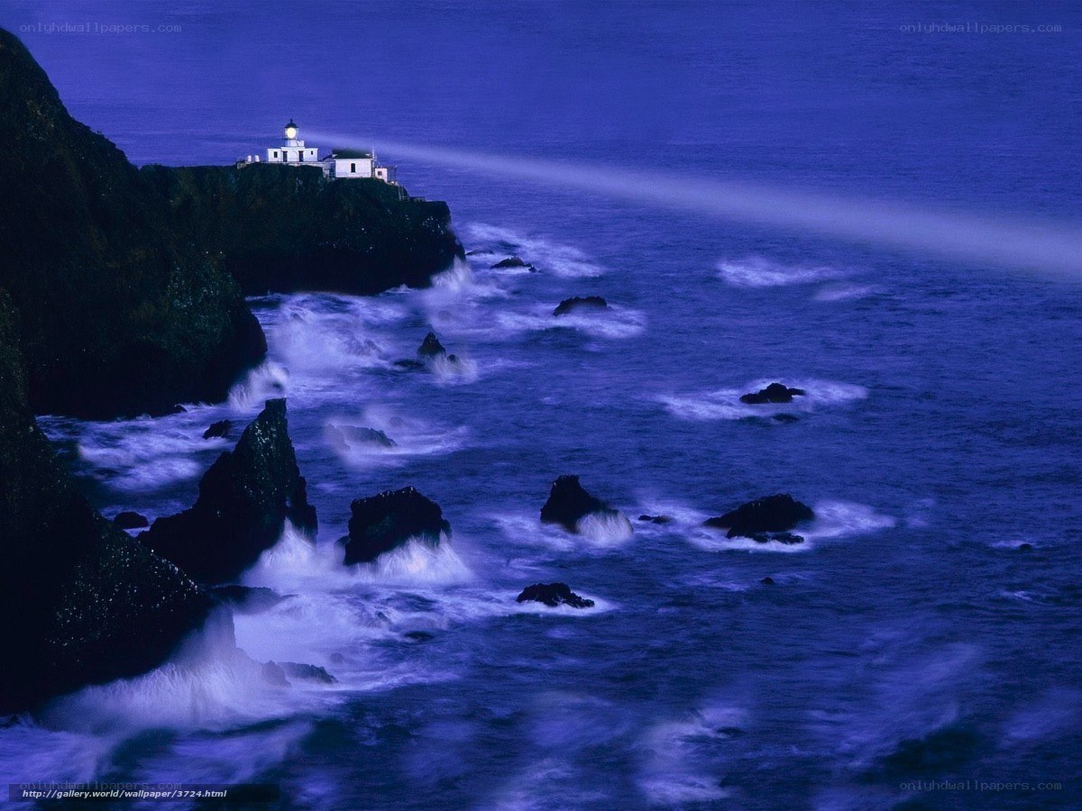 Lighthouse on rocky coast at night