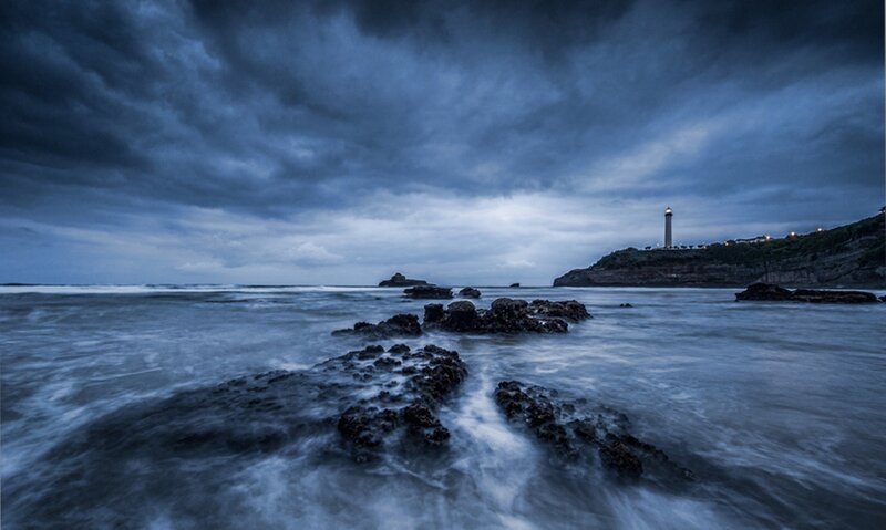 Lighthouse on Rocky Coast — Blue, Dramatic, Night, Photograph, Ocean, Rocks, Clouds