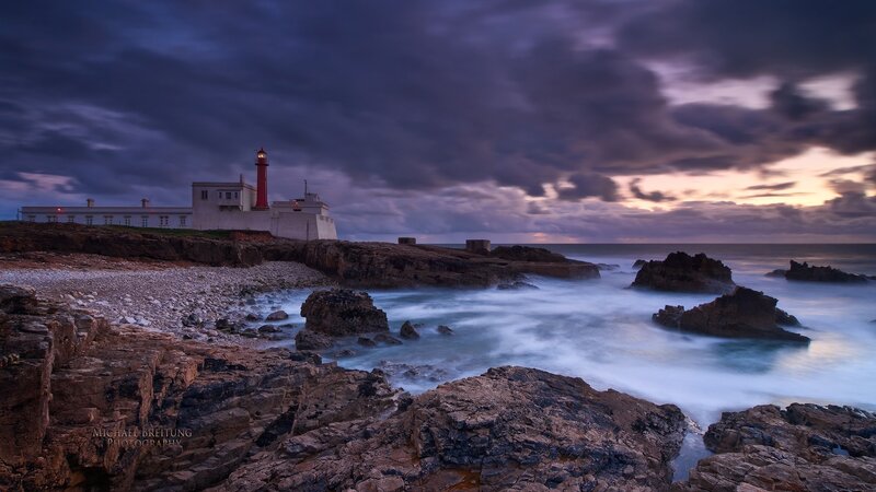 Lighthouse on Rocky Coast — Blue, Dramatic, Sunset, Photograph, Ocean, Rocks, Clouds