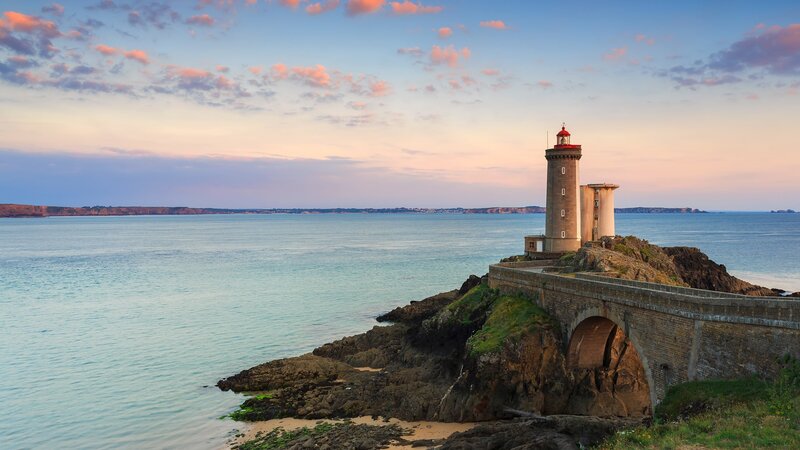 Lighthouse on Rocky Coast — Blue, Serene, Sunset, Photograph, Sea, Sky