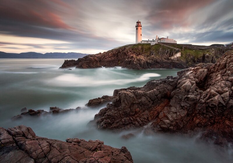 Lighthouse on Rocky Coast — Gray, Dramatic, Sunset, Photograph, Sea