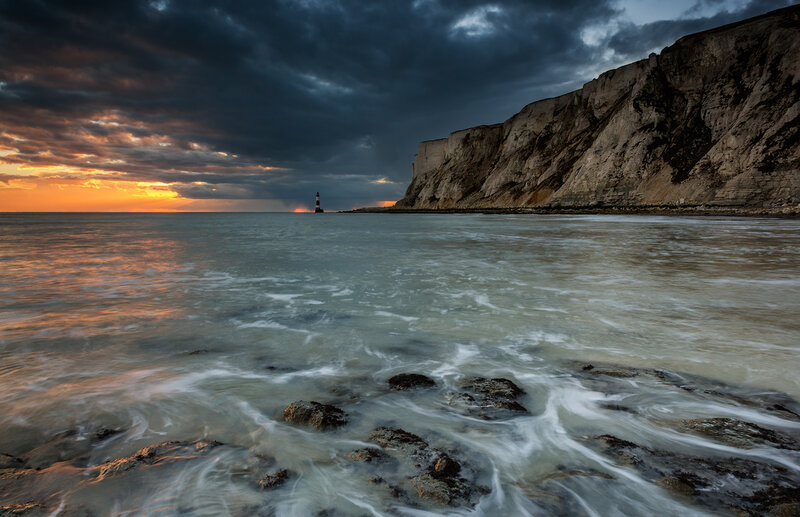 Lighthouse on Rocky Coast — Orange, Dramatic, Sunset, Photograph, Cliffs
