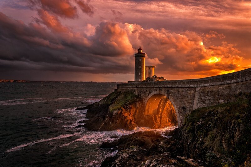 Lighthouse on Rocky Coast — Orange, Dramatic, Sunset, Photograph, Sea, Bridge