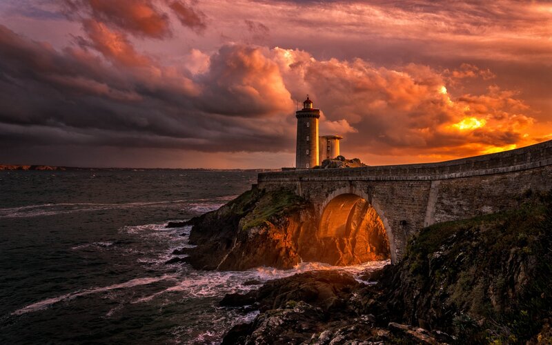 Lighthouse on Rocky Coast — Orange, Dramatic, Sunset, Photograph, Sea, Clouds