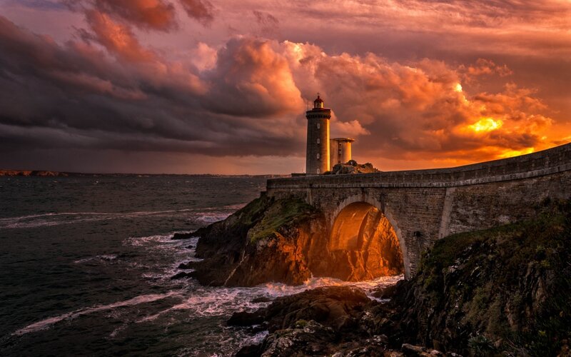 Lighthouse on Rocky Coast — Orange, Dramatic, Sunset, Photograph, Sea