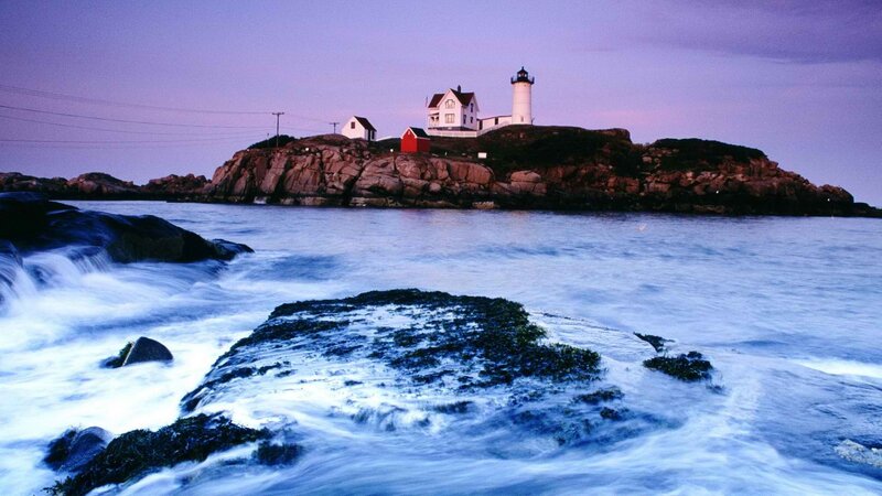 lighthouse on rocky island at dusk