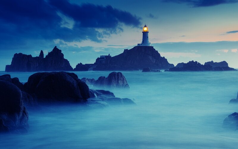 Lighthouse on rocky island at dusk