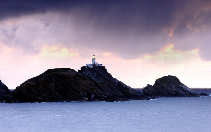 lighthouse on rocky island at dusk