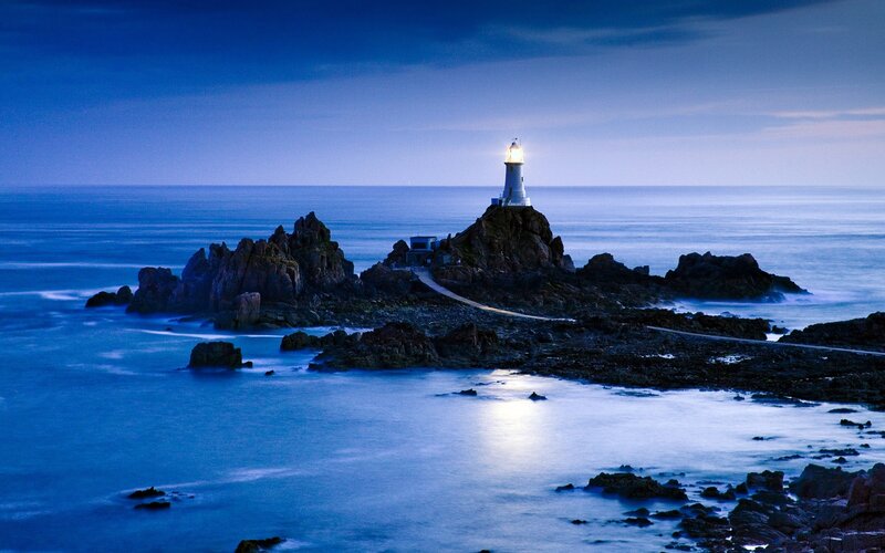 Lighthouse on rocky island at dusk