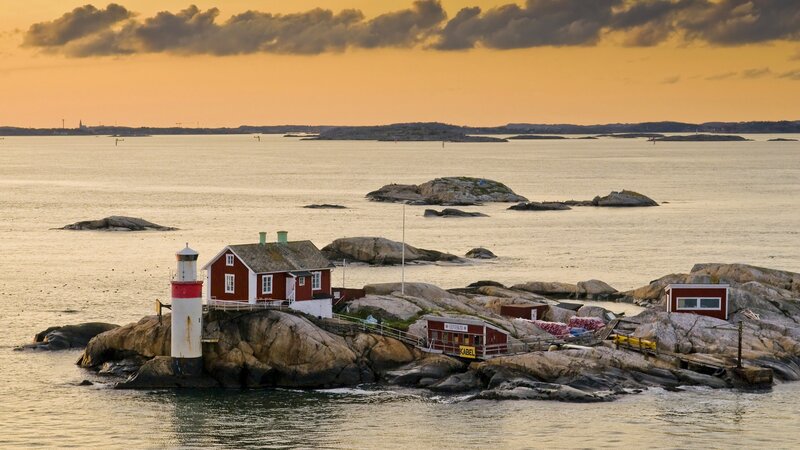 lighthouse on rocky island at sunset