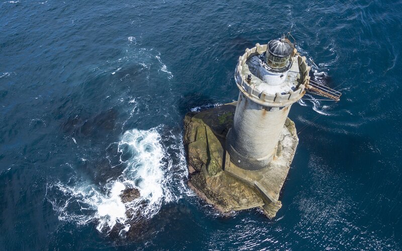 Lighthouse on Rocky Island — Blue, Dramatic, Afternoon, Photograph, Ocean, Waves, Rock