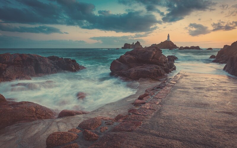 Lighthouse on Rocky Island — Blue, Dramatic, Sunset, Photograph, Ocean, Rocks, Path