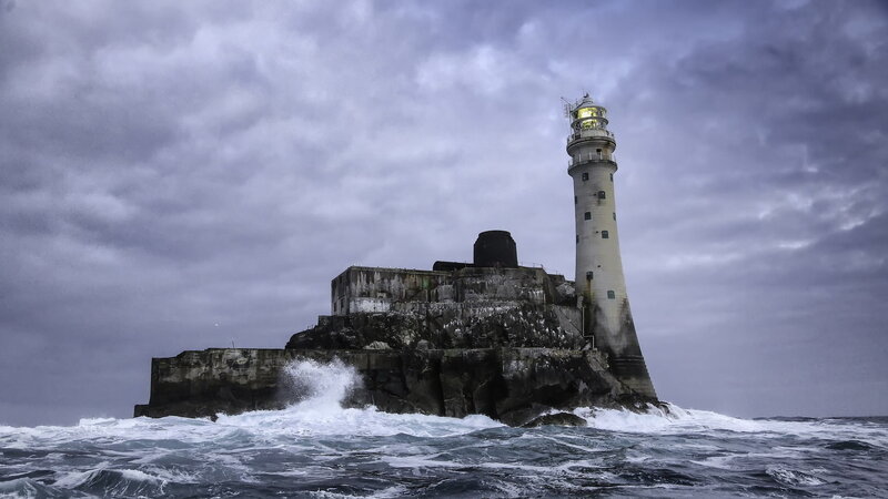 Lighthouse on Rocky Island — Gray, Dramatic, Photograph, Ocean Waves