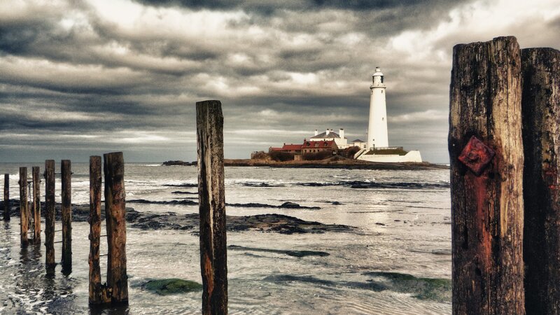 Lighthouse on Rocky Island — Gray, Dramatic, Photograph, Wooden Posts