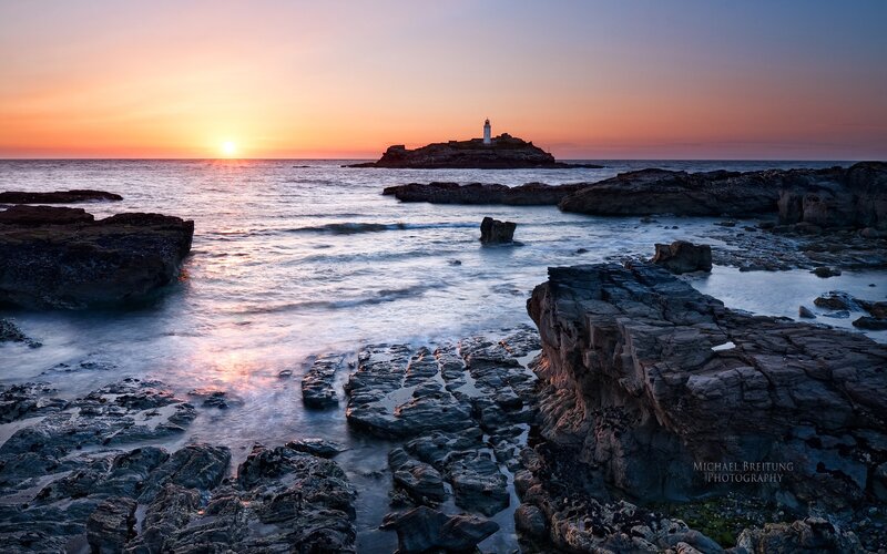 Lighthouse on Rocky Island — Orange, Serene, Sunset, Photograph, Sun, Ocean