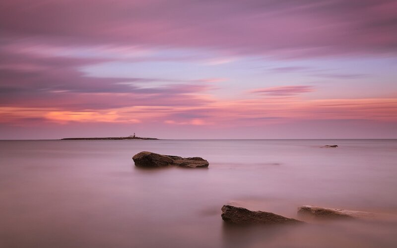 Lighthouse on Rocky Island — Purple, Serene, Sunset, Photograph, Rocks, Sea