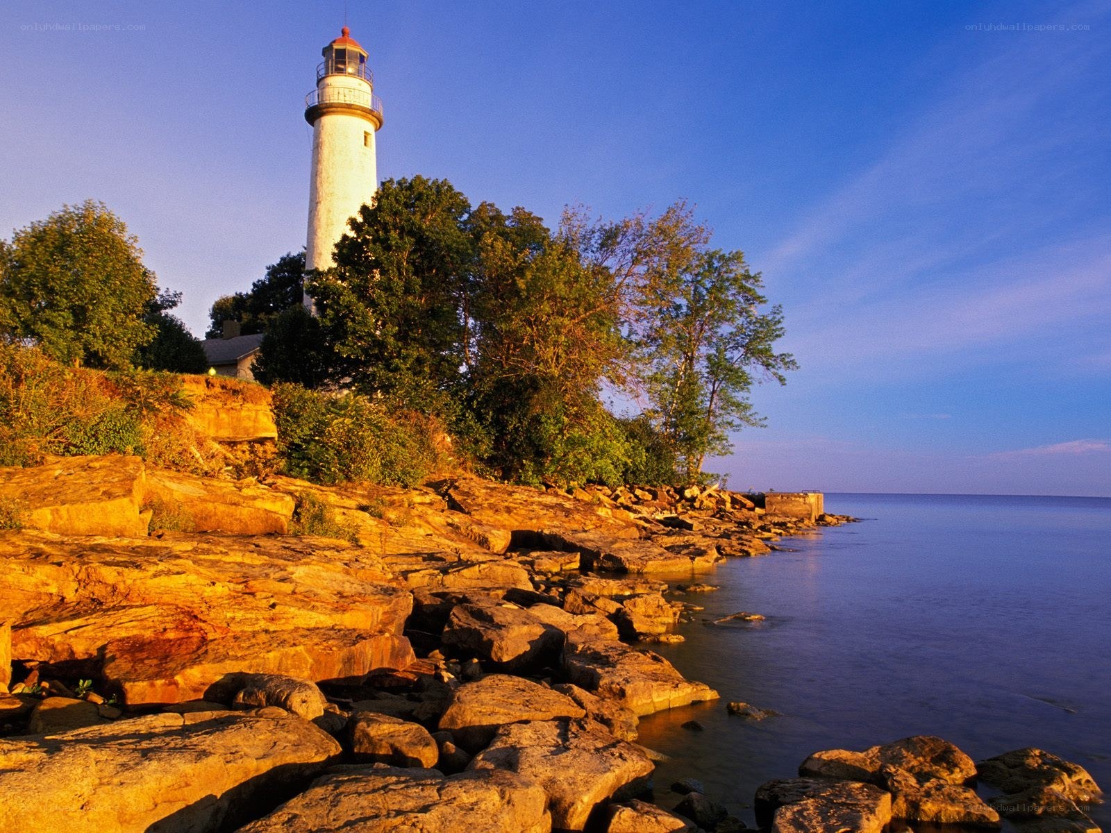 Lighthouse on rocky shore at sunset