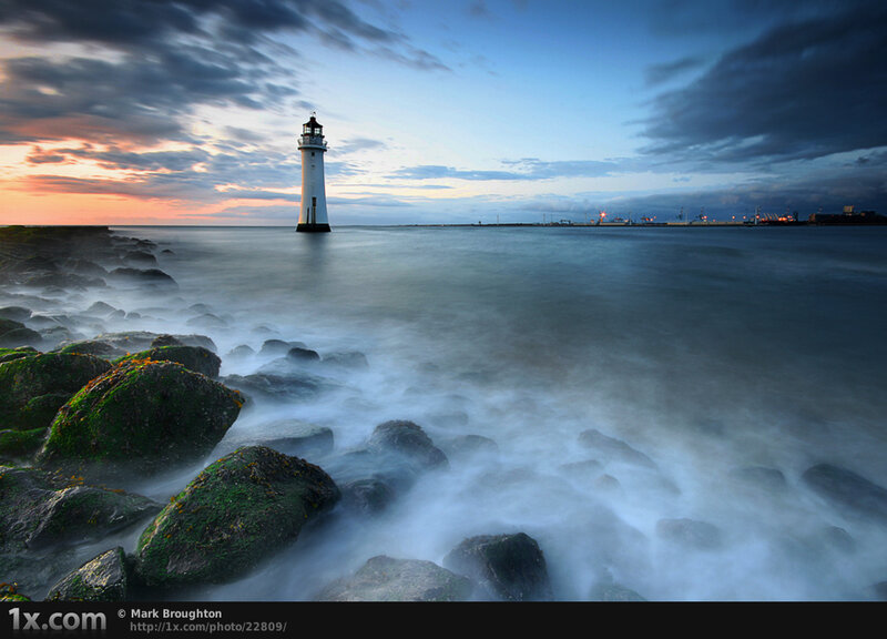 Lighthouse on Rocky Shore — Blue, Dramatic, Sunset, Photograph, Rocks