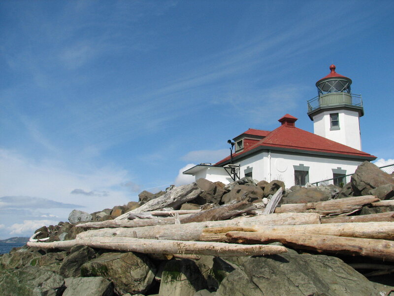 Lighthouse on Rocky Shore — Blue, Serene, Afternoon, Photograph, Rocks, Driftwood