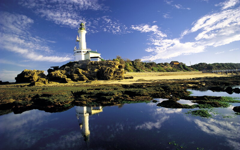 Lighthouse on Rocky Shore — Blue, Serene, Afternoon, Photograph, Rocks