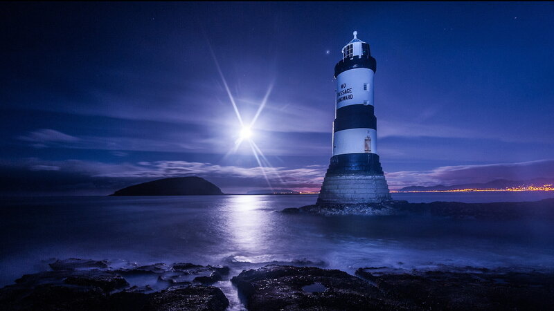 Lighthouse on Rocky Shore — Blue, Serene, Night, Photograph, Moon, Sea